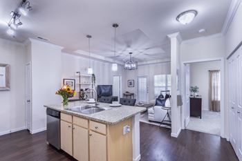 A kitchen with a sink, cabinets, and a counter.